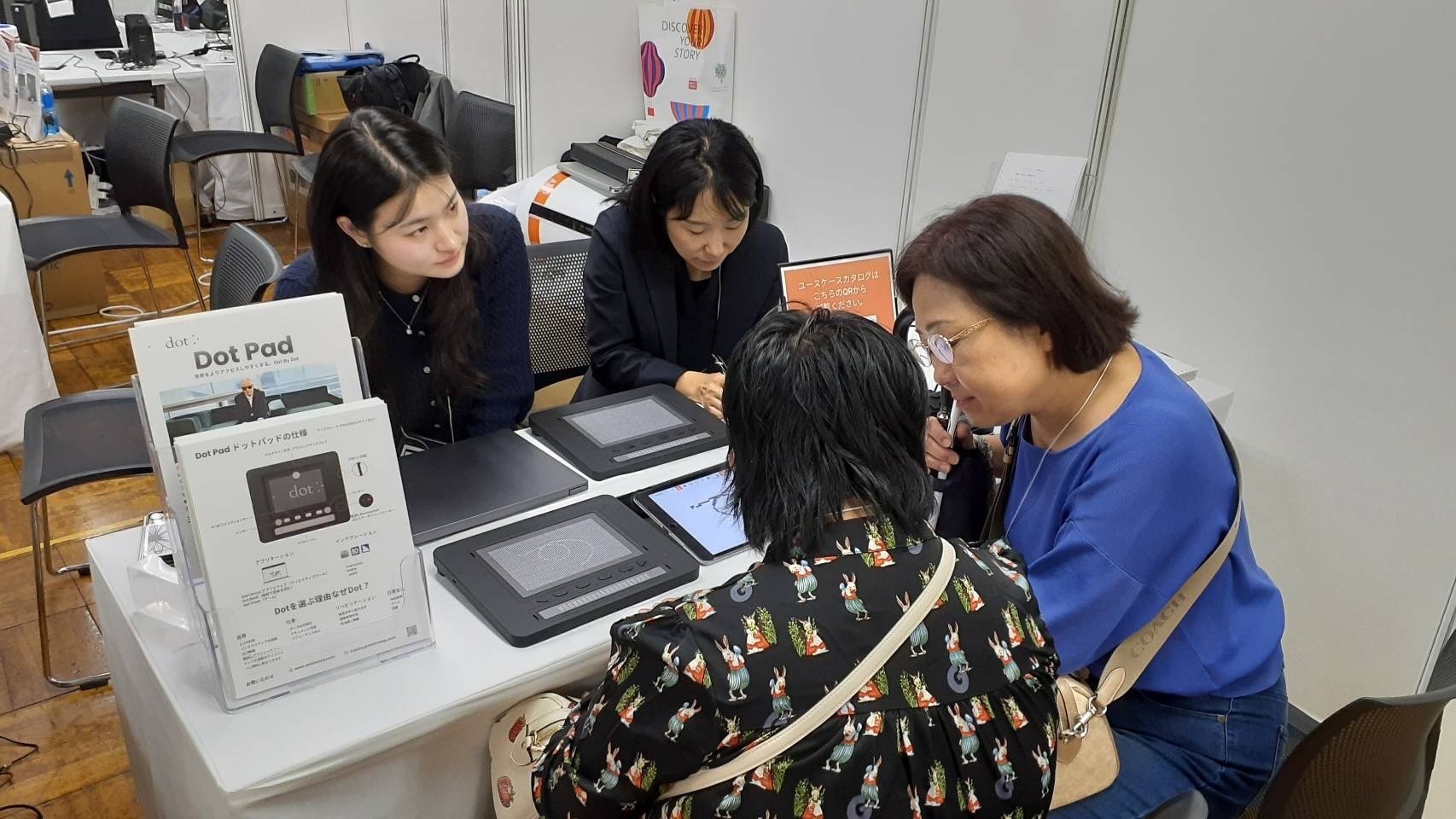 2 ladies are shown the Dot Pad X at an event
