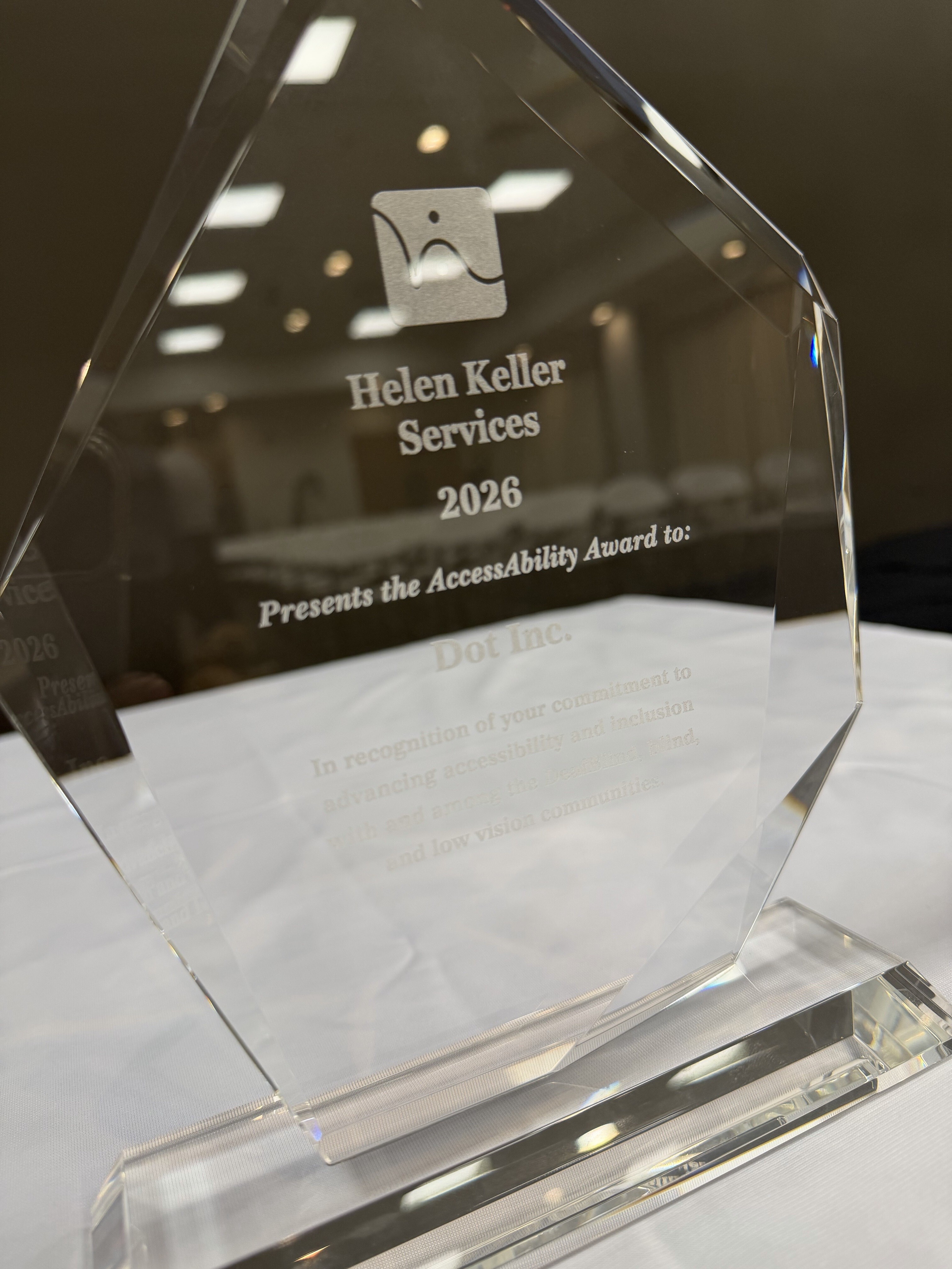 A clear glass award embossed with Helen Keller Services 2026 presents the Access Ability Award to Dot Inc. in recognition of your commitment to advancing accessibility and inclusion